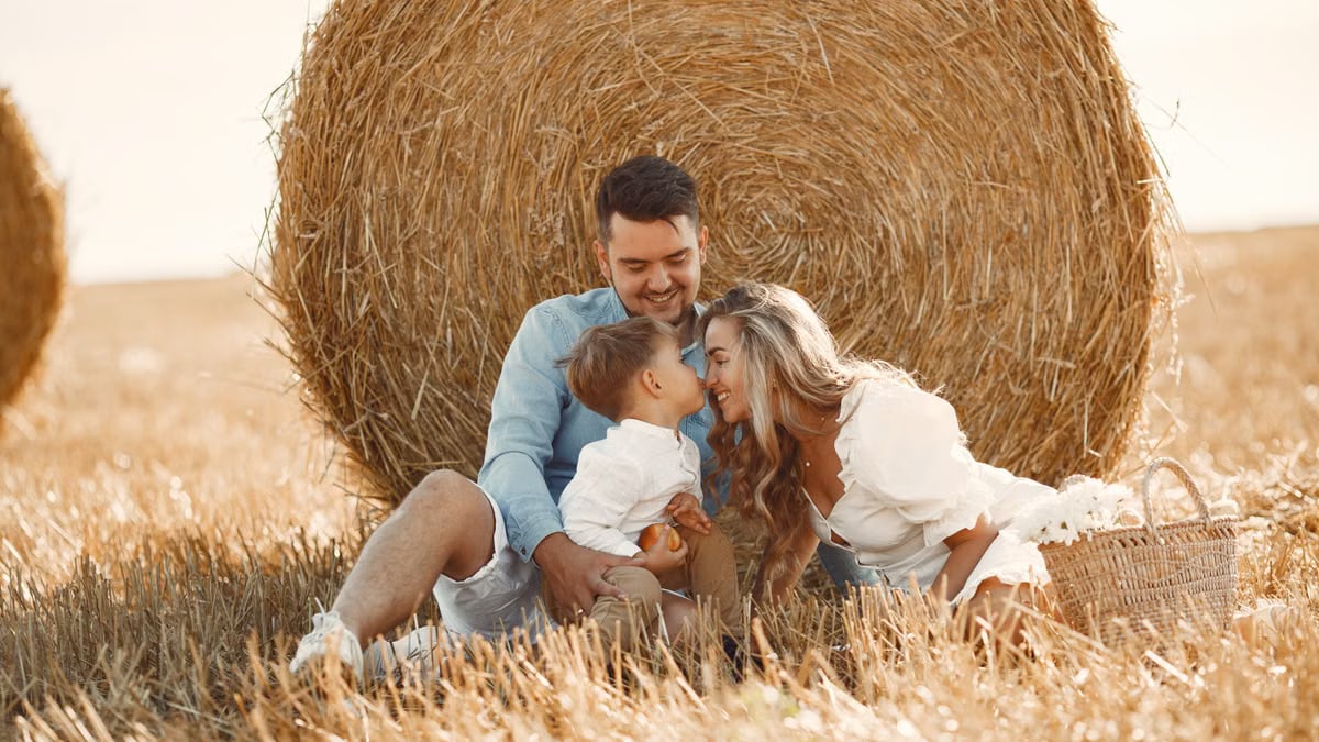 A happy family enjoying time together in a sunny, rural hay field, showcasing warmth and bonding.