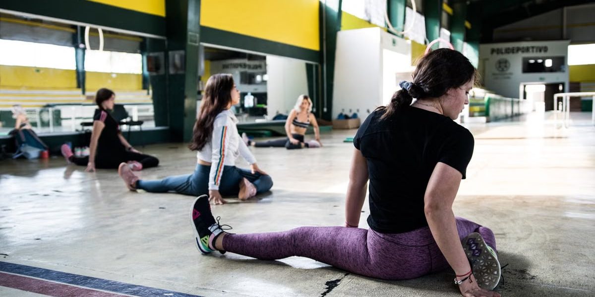 Women engaging in a group stretching session in an indoor gym.