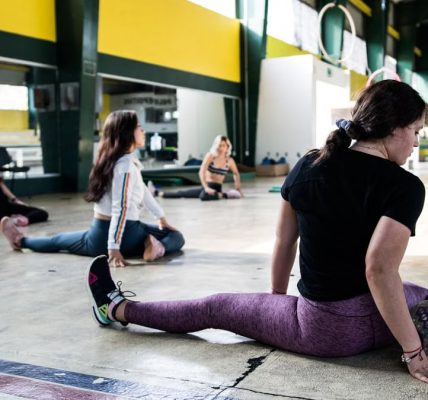Women engaging in a group stretching session in an indoor gym.